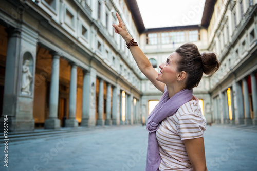 Young woman pointing near uffizi gallery in florence, italy photo