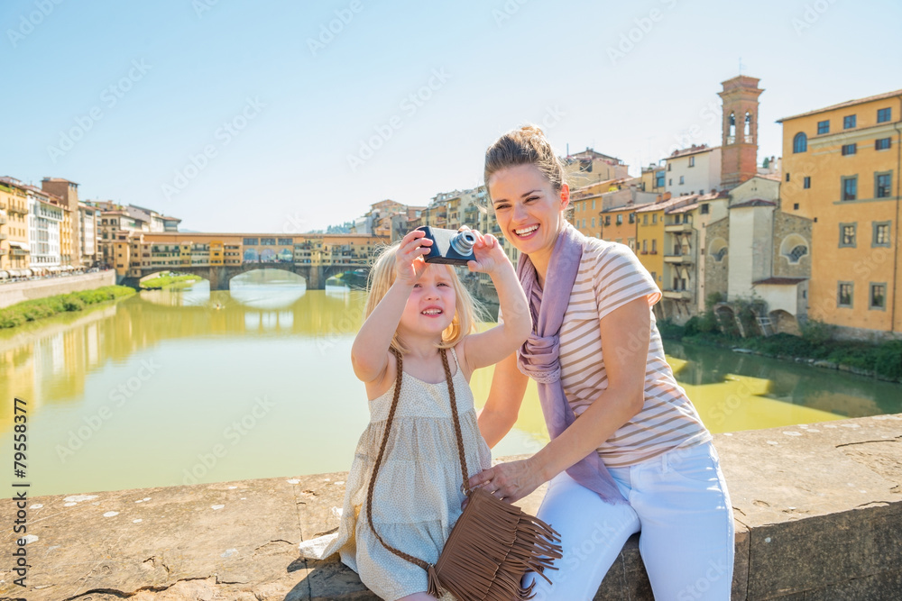 Mother and baby girl taking photo on bridge in firenze