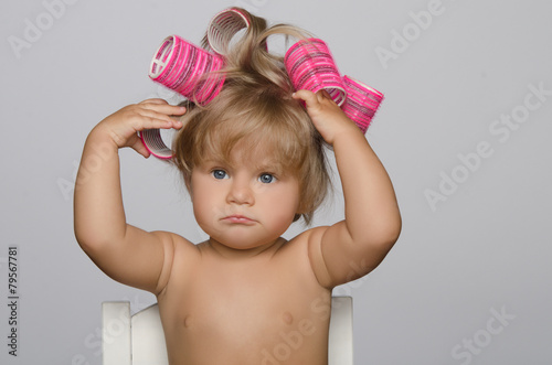 Little attractive kid with hair curlers photo