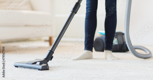 close up of woman legs with vacuum cleaner at home