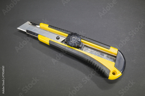 Utility knife with yellow plastic handle and rubber insert