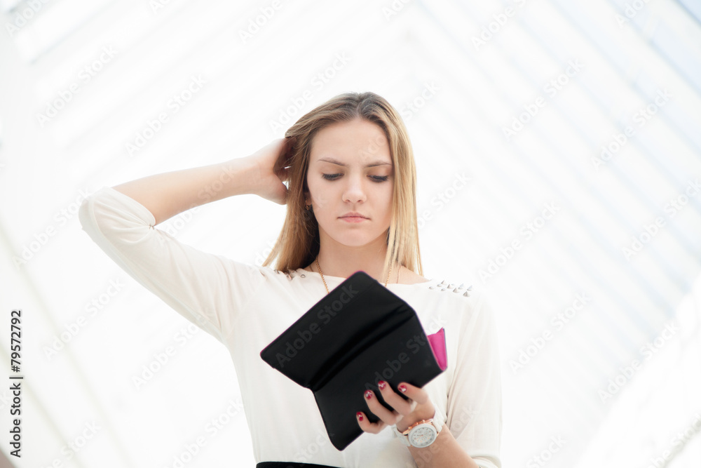 Depressed young woman looking into her purse in dismay Depressed young woman looking into her purse in dismay