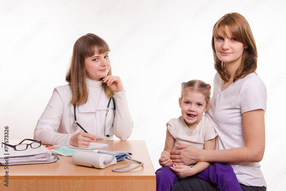 Pediatrician, child and his mother are sitting at desk in office Pediatrician, child and his mother are sitting at desk in office