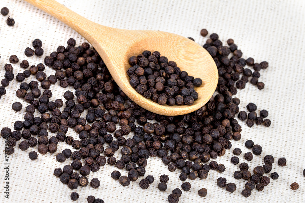 closeup black pepper in wooden spoon on fabric closeup black pepper in wooden spoon on fabric