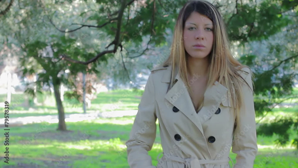 Serious beautiful girl walking in the park. She looking at camera Serious beautiful girl walking in the park. She looking at camera