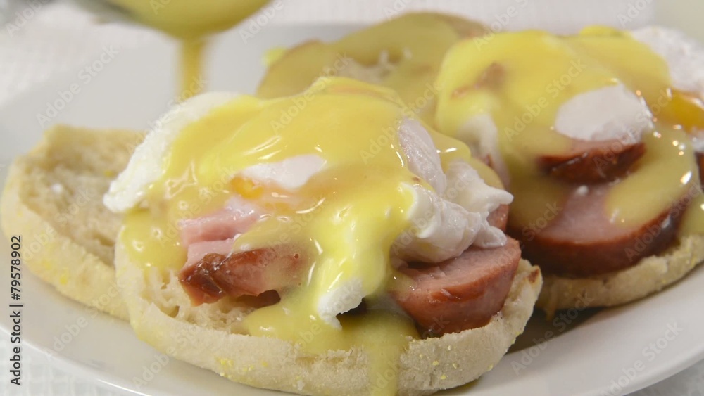 Pouring hollandaise sauce on eggs Benedict Pouring hollandaise sauce on eggs Benedict