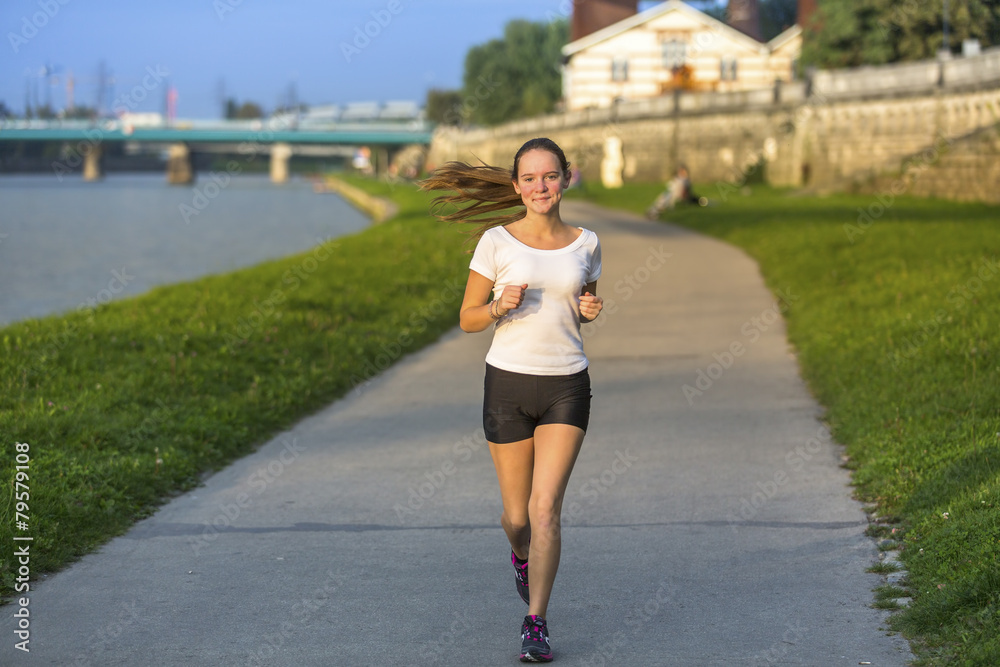 Young girl running on treadmill along river in the big city. Young girl running on treadmill along river in the big city.