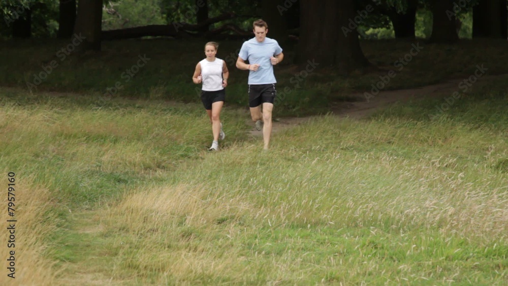 Male and female running trough park Male and female running trough park