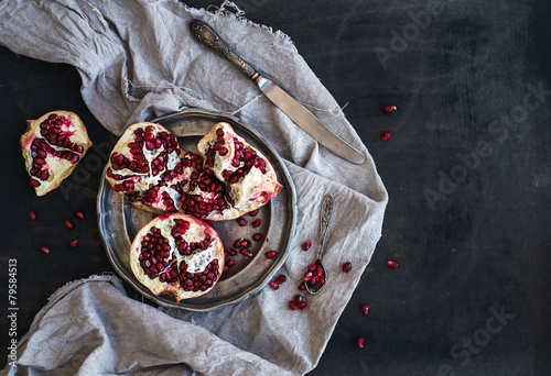 Red ripe peeled pomegranate on rustic metal plate