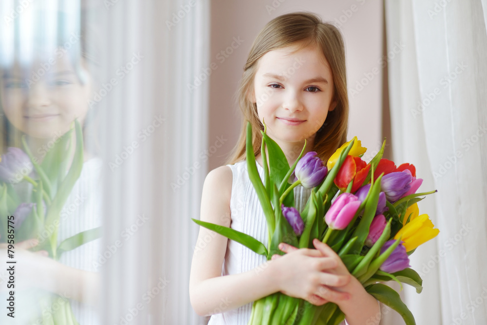 Adorable little girl holding tulips by the window Adorable little girl holding tulips by the window