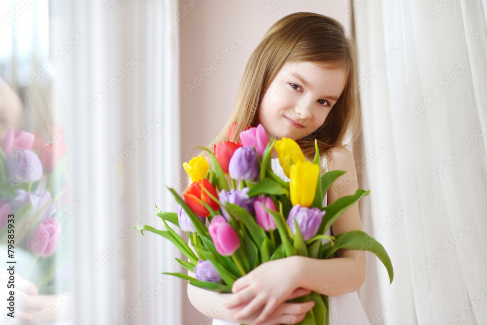 Adorable little girl holding tulips by the window Adorable little girl holding tulips by the window