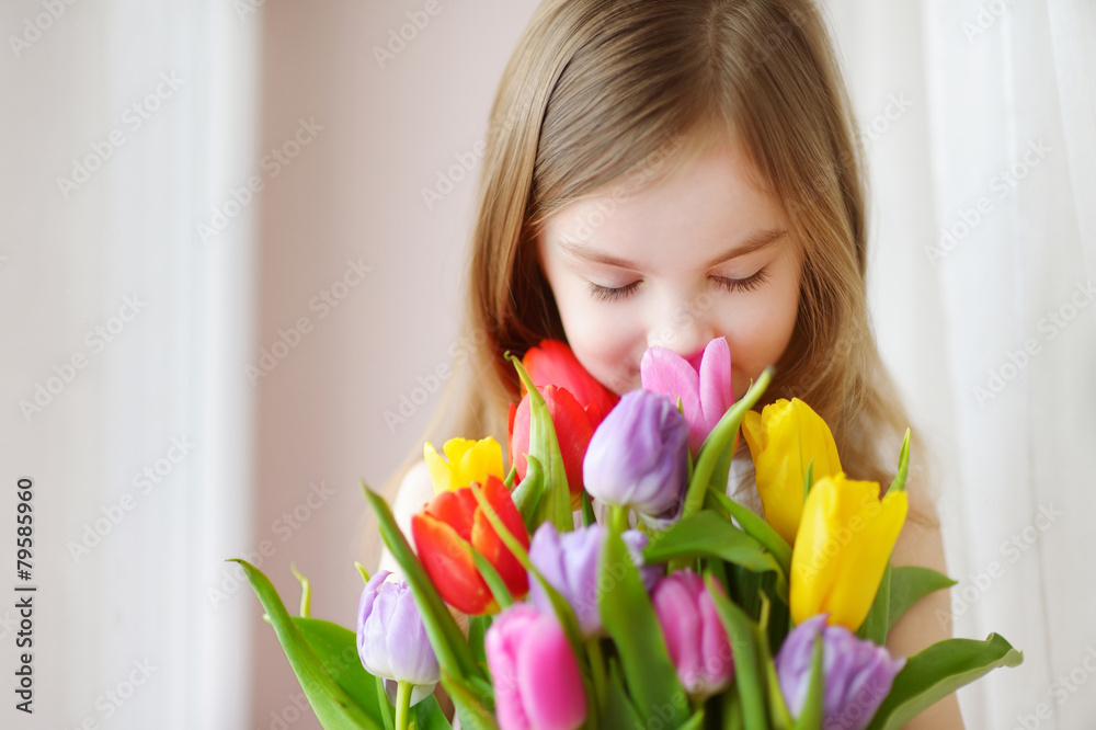 Adorable little girl holding tulips by the window Adorable little girl holding tulips by the window