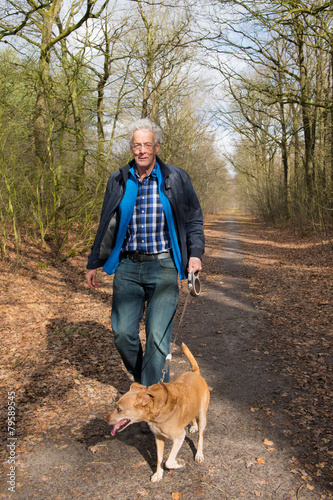 Senior man walking dog in forest
