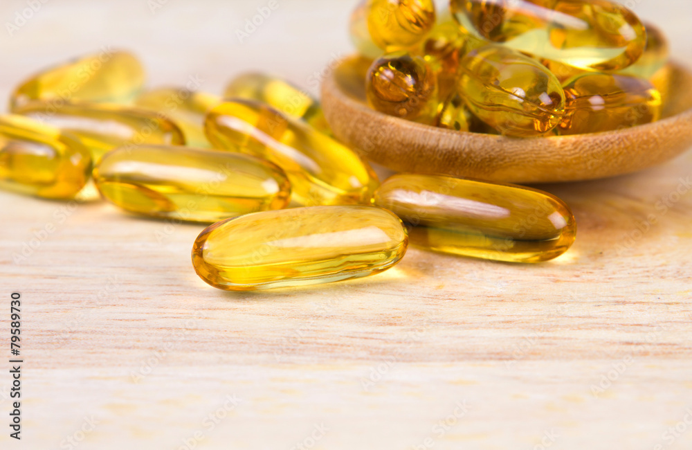 Closeup yellow soft gelatin supplement fish oil capsule on woode Closeup yellow soft gelatin supplement fish oil capsule on woode