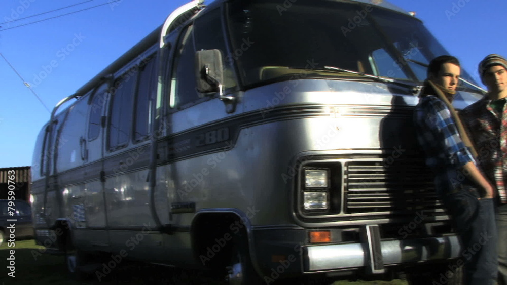 Pan out left on two boys in front of camper Pan out left on two boys in front of camper