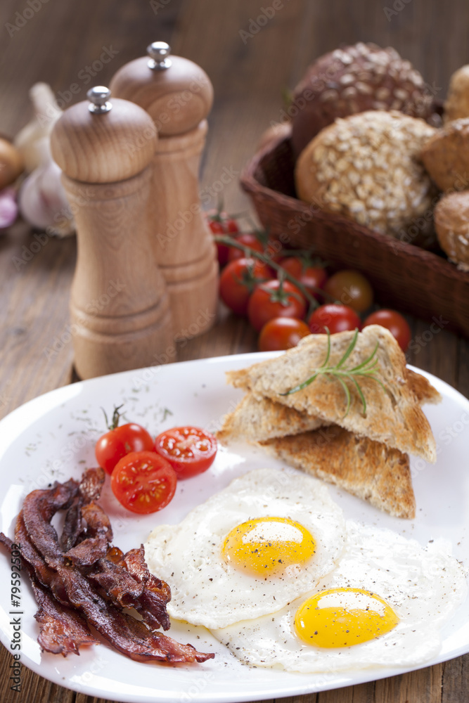 Fried egg and bacon on a plate with spices and vegetables Fried egg and bacon on a plate with spices and vegetables