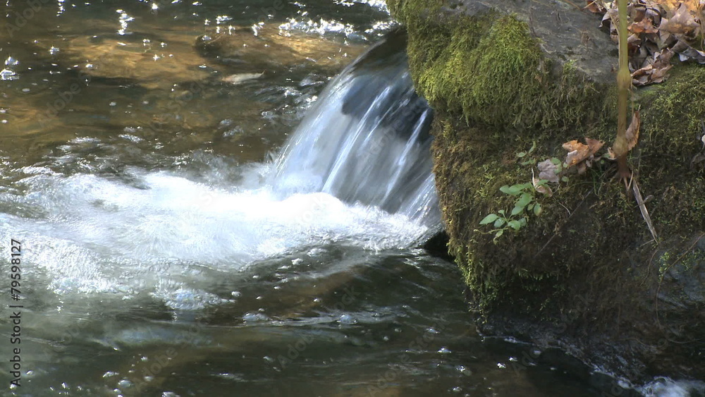 Water splashes moss covered rocks. Water splashes moss covered rocks.