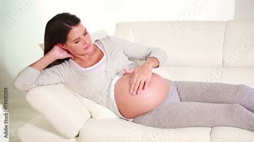 one pregnant woman applying cream on her stomach