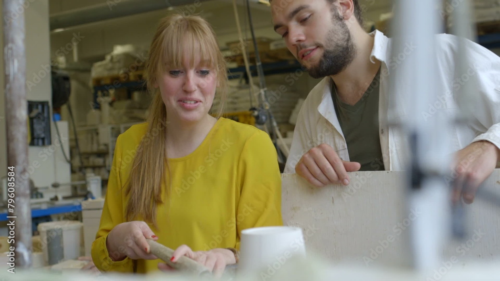 Male potter teaching pottery to woman Male potter teaching pottery to woman