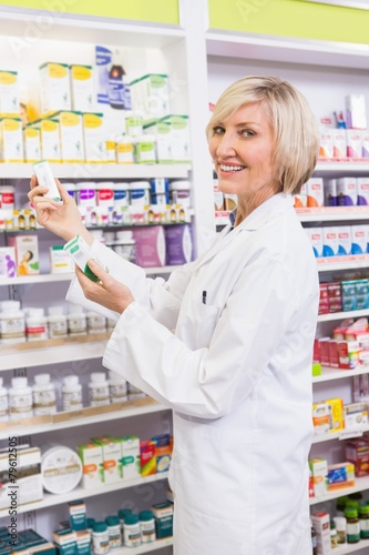 Smiling pharmacist holding boxes of medicine
