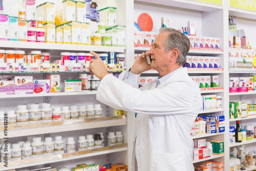 Focused pharmacist on the phone pointing medicine Focused pharmacist on the phone pointing medicine