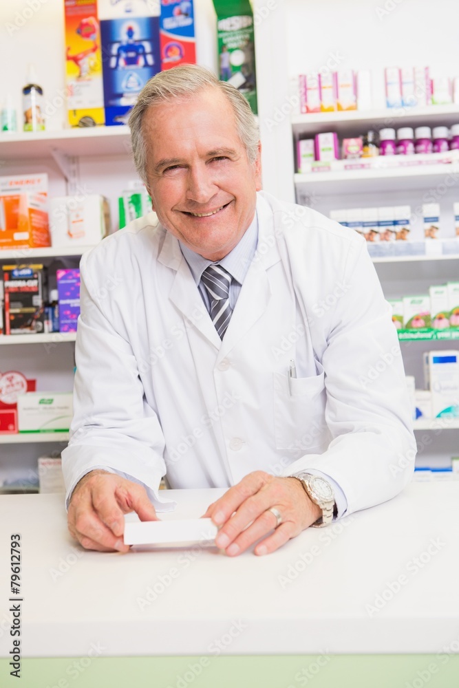 Senior pharmacist leaning on the counter holding prescription