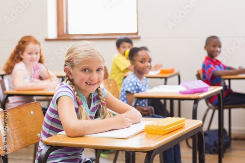 Smiling pupils sitting at her desk