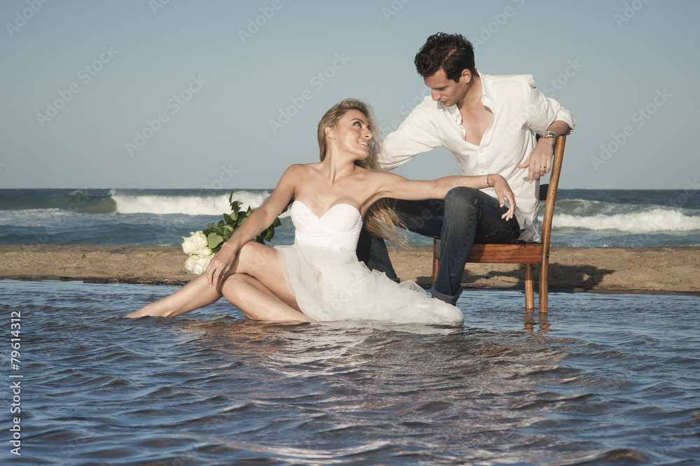 Young beautiful couple sitting at water's edge flirting in love Young beautiful couple sitting at water's edge flirting in love