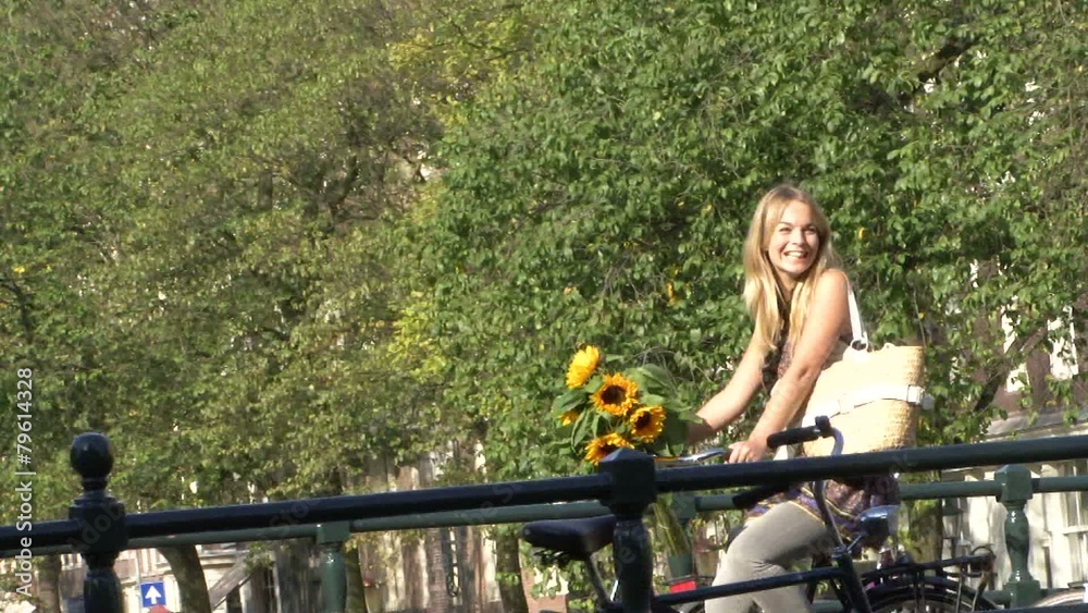 Female cycling over bridge in amsterdam and waving to friend