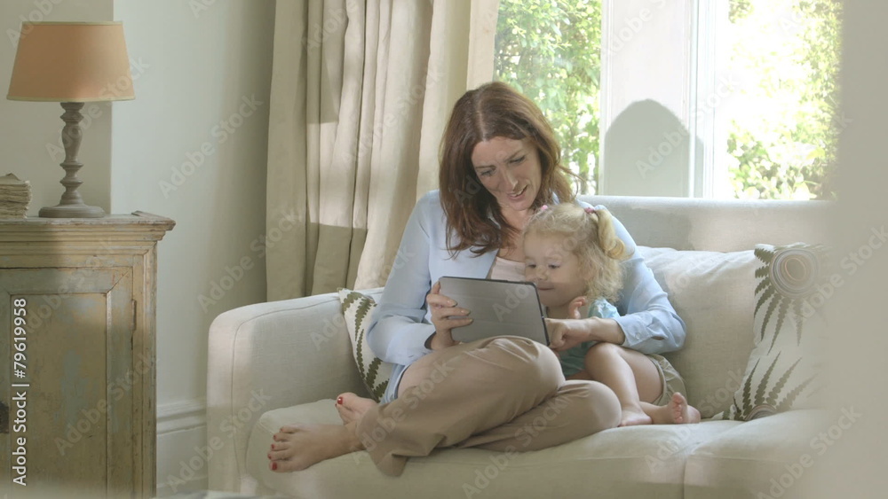 Mother showing digital tablet to her daughter Mother showing digital tablet to her daughter