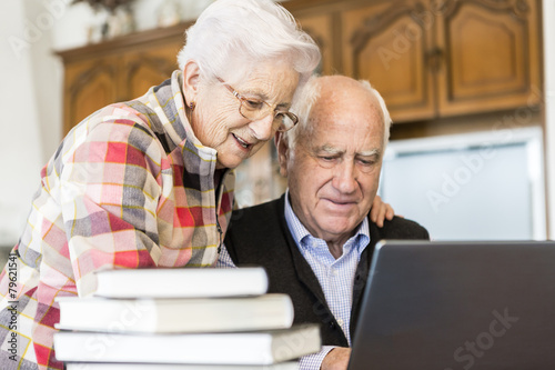 Senior couple looking for information in books and internet © photopitu