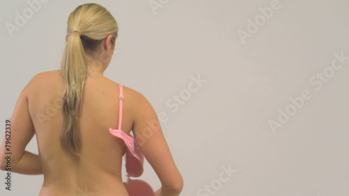 MS OF A YOUNG WOMAN REMOVING A BRA