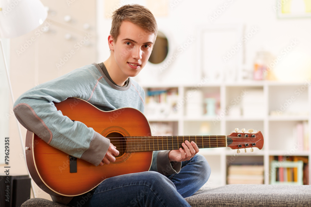© cherryandbees - Young man playing guitar at his home