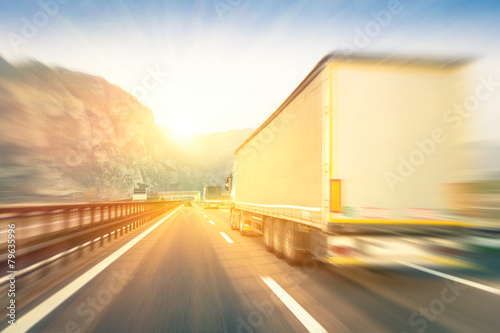 Semi trucks speeding on the highway at sunset