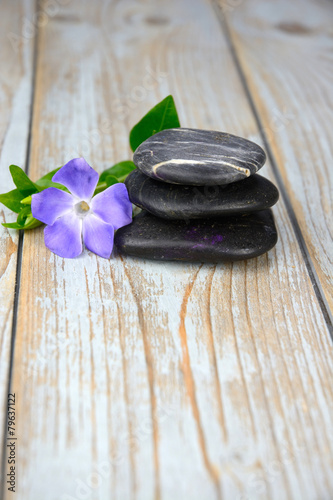 Black zen stones with purple flower on old wood