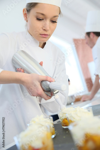 Canvas Print Pastry cook spreading whipped cream on dessert
