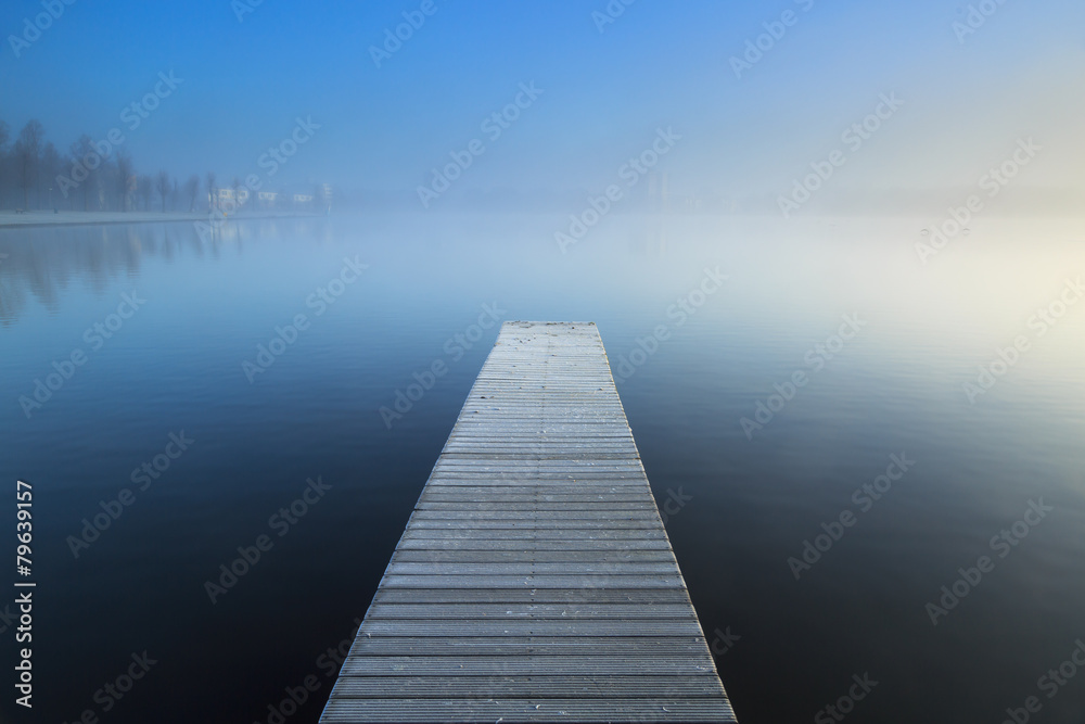 Empty jetty in a foggy lake during sunrise. - obrazy, fototapety, plakaty 