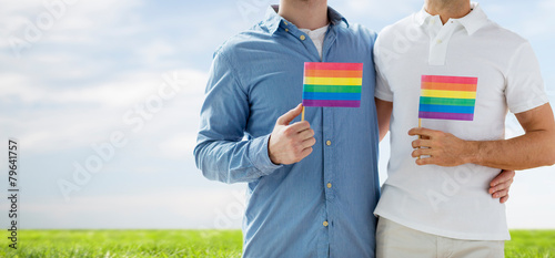 close up of male gay couple holding rainbow flags