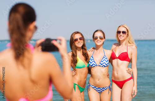 group of smiling women photographing on beach © Syda Productions