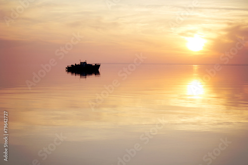 silhouette of a floating boat at sunset
