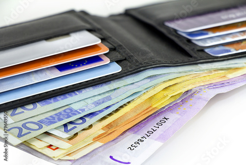 A bundle of Euro banknotes and credit cards in a black leather wallet