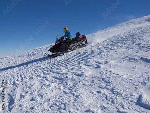 The man riding on the snowmobile.