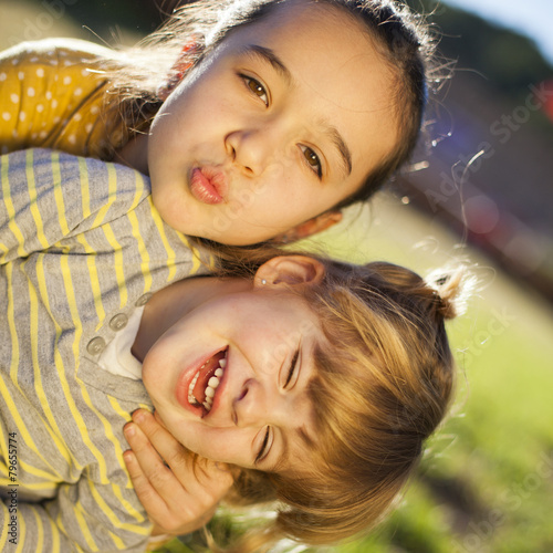 Niña lanzando un beso mientras abraza a su amiguita photo