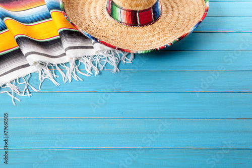 Mexican background with sombrero straw hat and traditional serape rug or blanket on old blue planked wood Mexico holiday vacation cinco de mayo photo