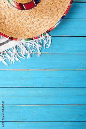 Mexican background with sombrero straw hat and traditional serape rug or blanket on old blue planked wood Mexico holiday vacation cinco de mayo photo vertical