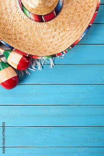 Mexican background with sombrero straw hat maracas and traditional serape rug or blanket on old blue planked wood Mexico holiday vacation cinco de mayo photo vertical