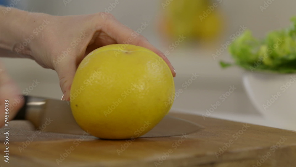 Close shot of woman slicing grapefruit in half Close shot of woman slicing grapefruit in half