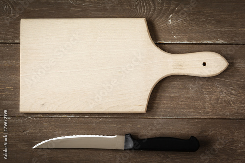 Schneidbrett mit Messer auf Holzuntergrund photo