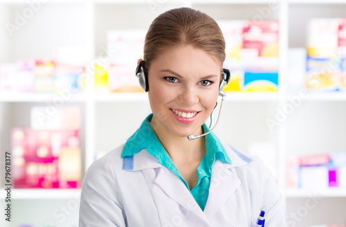 Young woman pharmacist chemist servicing customer on phone