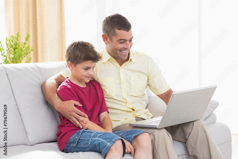 Happy father and son using laptop on sofa Happy father and son using laptop on sofa